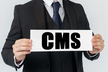 A businessman holds a sign in his hands which says CMS CONTENT MANAGEMENT SYSTEM