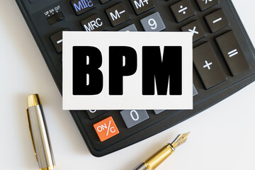 On the table there is a pen, a calculator and a business card on which the text is written BPM....