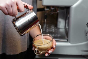 Closeup of barista pouring milk into art cappuccino or latte