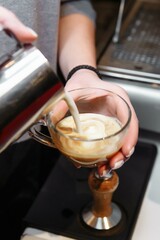 Closeup of barista pouring milk into art cappuccino or latte