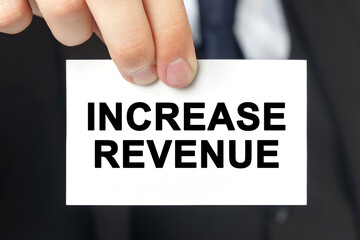Businessman shows a card with the text INCREASE REVENUE