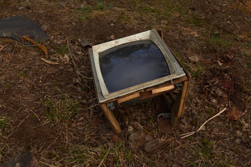 old broken TV on the ground with a black screen
