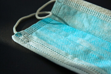 Blue soft surgical mask which can protect from the viruses and bacterias. Safety. Black background. Close up shot.