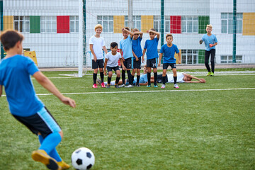 sportive child boy in uniform kicking ball, they have penalty in this round. kids play football, competition in stadium, in field