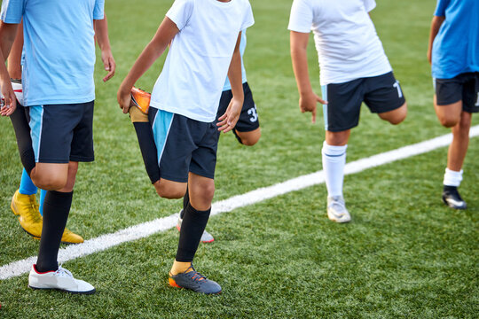 group of caucasian kid boys stretching legs before football game in stadium, they are in special sportive uniform, engaged in sport and healthy lifestyle from childhood