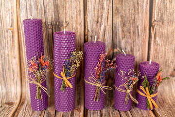 Purple honey candles handmade from natural wax on a background of wooden boards. Elements from natural materials. Christmas or New Year's composition. Photo for postcards.