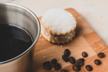 Italian lack coffee in a cup with coffee beans and a handmade cookie with sugar and a moka pot behind. Everything in vintage brown background close to the window.