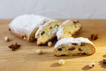 sliced of traditional German Christmas pastries on wooden background. delicious cake stollen with nuts, raisins, dried fruits and spices close up on the table