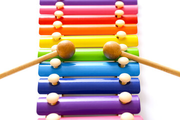 Rainbow colored wooden toy xylophone with two sticks on white background. Close up