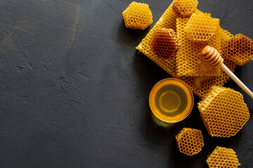 Honey with honeycomb on black table, top view. space for text
