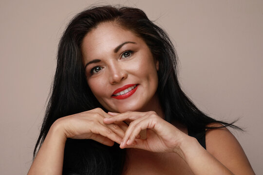 Mature Hispanic woman with red lips, posing and smiling over white background.