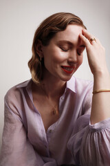 Fototapeta premium Side portrait of smiling young woman with red lips wearing golden jewellery. Vertical close-up of beautiful woman.