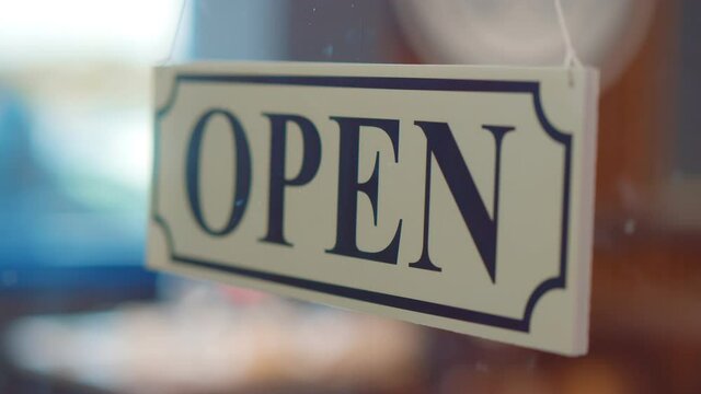 Close up of owner turning closed sign at bar or restaurant glass door or window