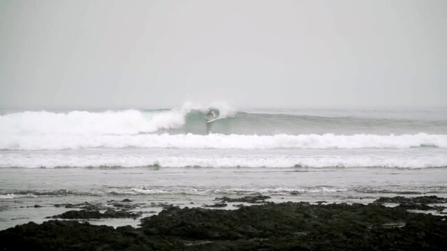 Surfer riding and turning with spray on powerful ocean wave.Surfing ocean lifestyle.