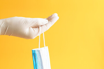 Surgical mask and gloves on a yellow background.