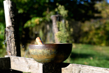 Tibetan singing bowl on a wooden fence. Translation of mantras. transform your impure body, speech and mind