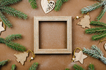 Christmas background with fir branches and wooden ornaments on a brown table. 