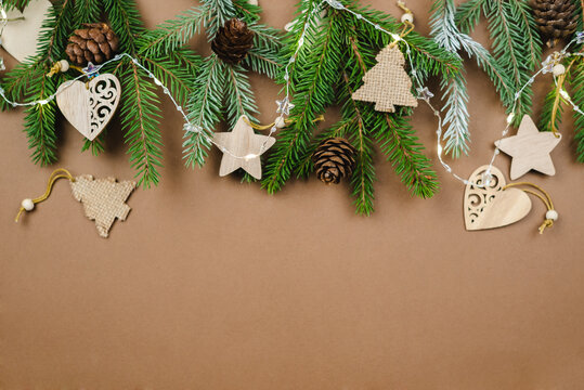 Christmas background with fir branches and wooden ornaments on a brown table. 