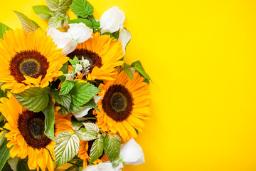Bright juicy bouquet of sunflowers and white eustomas on a bright yellow background. Layout.
