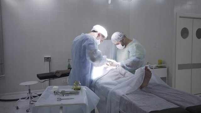Two professoinal surgeons performing phimosis surgery. Action. Male health concepts, medical procedure on male penis in sterile operating room.