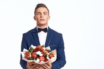 An elegant man in a classic suit with a bow tie holds a bouquet of flowers in his hand 