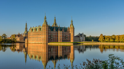 The Royal Frederiksborg Castle in a mirror-gloss reflection at surise