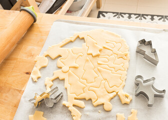 Circular mass of dough cut with metallic molds. Shapes are a pine tree, a person and a deer.