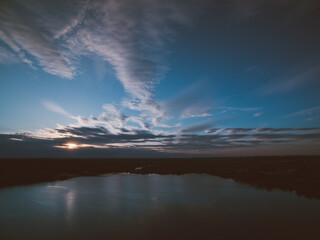 Sunset over a river with forest and a city on horizon. Almost dusk.