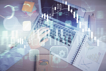 Double exposure of man's hands typing over computer keyboard and forex graph hologram drawing. Top view. Financial markets concept.