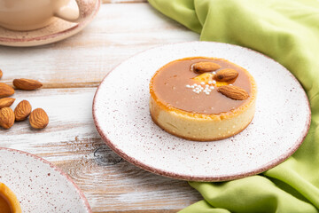 Sweet tartlets with almonds and caramel cream with cup of coffee on a white wooden background. side view, close up.