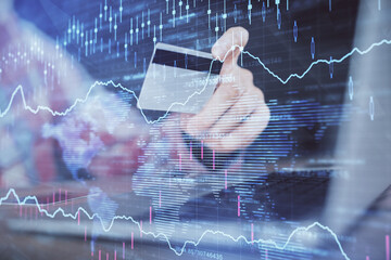 Double exposure of man hands holding a credit card and Forex graph drawing. Stock trading and digital fintech in Internet E-commerce concept.