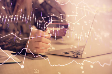 Multi exposure of woman on-line shopping holding a credit card and financial graph drawing. Stock market E-commerce concept.