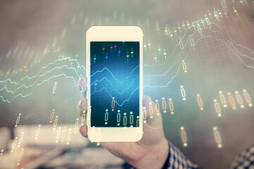 Double exposure of man's hands holding and using a digital device and forex graph drawing. Financial market concept.