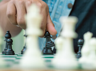 Chess game on a green board, a hand holds a black pawn