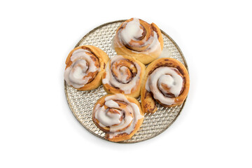 a plate full of five fresh cinnamon buns with cream cheese icing isolated on white