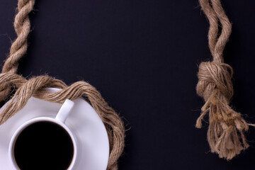 white coffee mug on a black background with a place for text decorated with a rope
