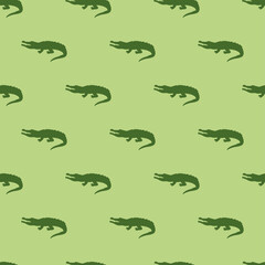 Animal seamless pattern and textile design. Vector illustration with green crocodile silhouette on light green background. Good for t-shirt design, fabric print, greeting card, wrapping, wallpapers.