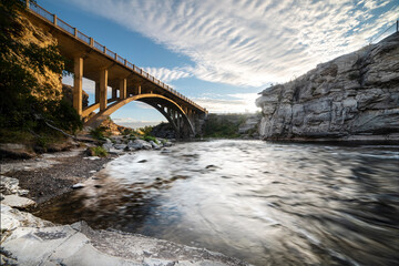 Bridge and fast moving water during sunrise at Lundbreck Falls, Alberta