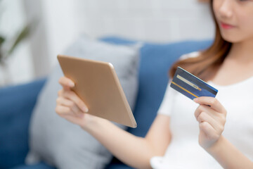Young asian woman smiling holding credit card shopping online with tablet computer buying and payment, girl using debit card purchase or transaction of finance, lifestyle and e-commerce concept.