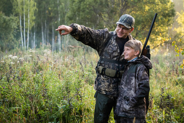 A young boy on the hunt with an experienced instructor in the forest. Autumn. Hunting for upland wildfowl. - 386534492