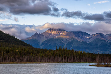 View of Scenic Lake surrounded by Mountains and Trees on a Cloudy Morning at Sunrise in Canadian Nature. Taken in Northern British Columbia, Canada.