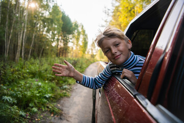 Cheerful child who is looking out of an open window of the car