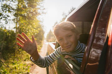 Cheerful child who is looking out of an open window of the car