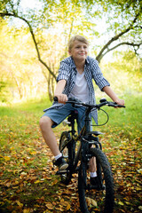 Boy rides the bike in the autumn forest