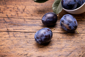 heap of a purple damsons plums over grunge wooden background. natural fruits. healthy eating concept