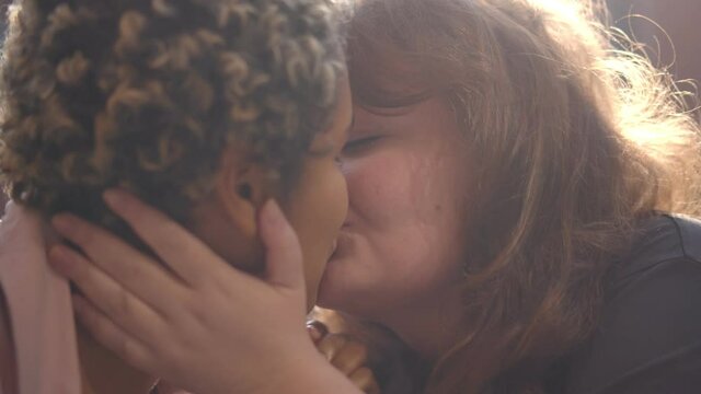 Close up of diverse women couple hugging and kissing on date outdoors