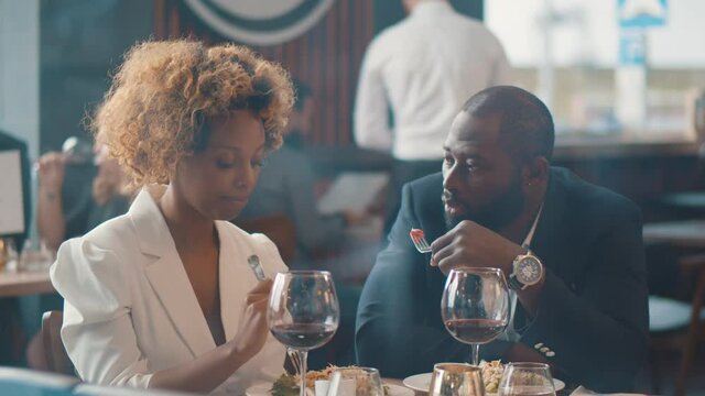 Portrait of cheerful beautiful afro-american couple dining in restaurant and talking