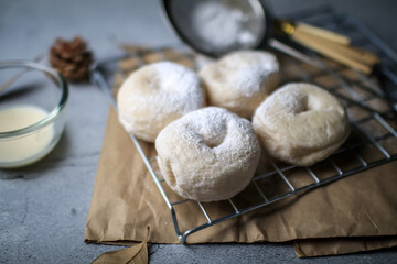 Delicious freshly baked doughnuts with powdered sugar on dark background. Breakfast concept, Selective focus.