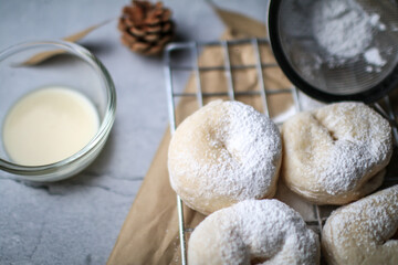 Delicious freshly baked doughnuts with powdered sugar on dark background. Breakfast concept, Selective focus.