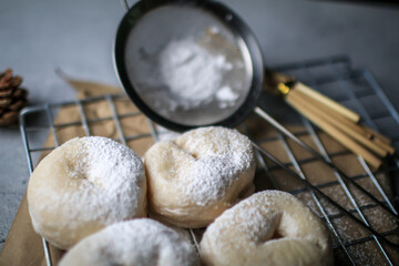 Delicious freshly baked doughnuts with powdered sugar on dark background. Breakfast concept, Selective focus.